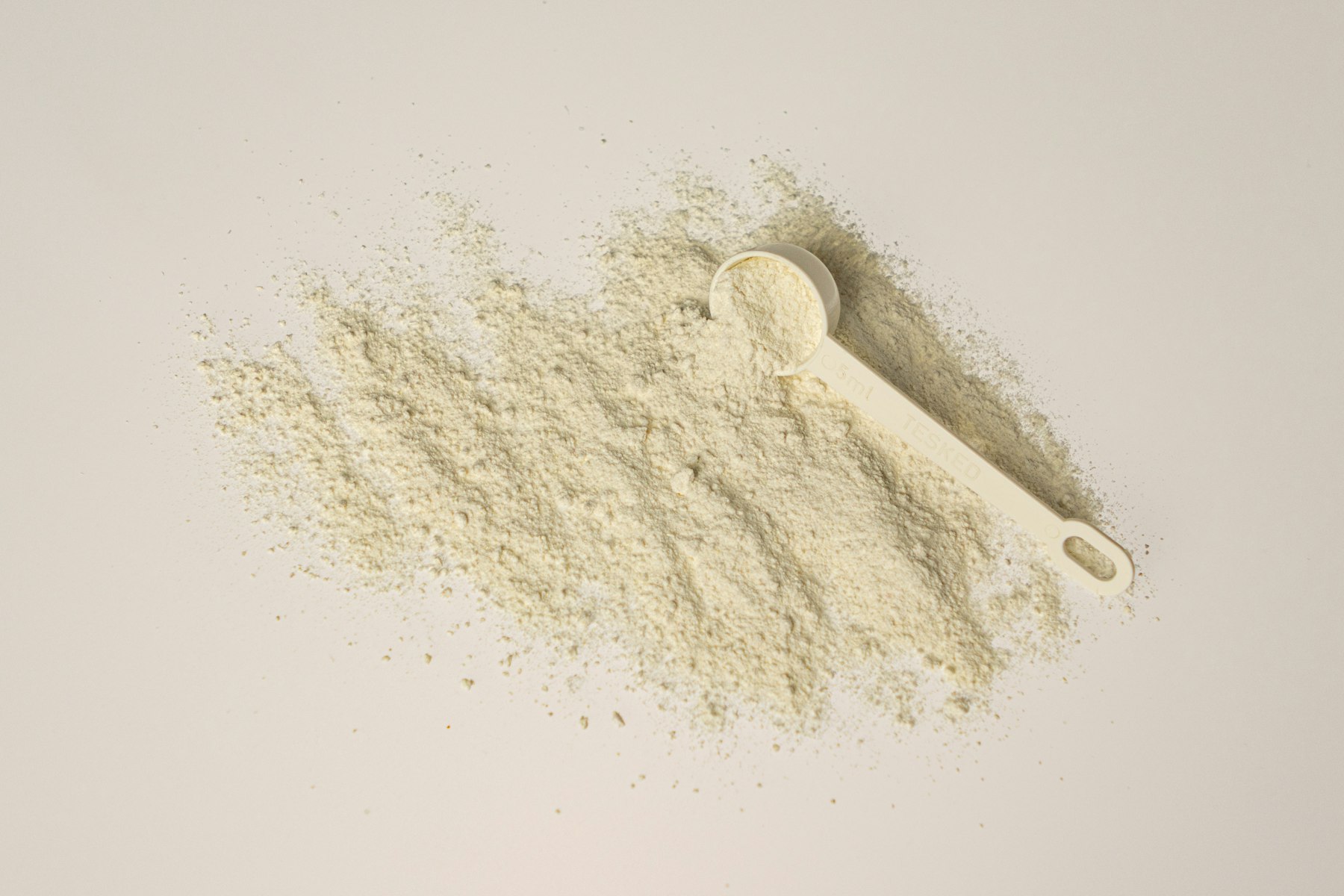 poudre de complément alimentaire mesurée avec une cuillère-dose sur un plan de travail