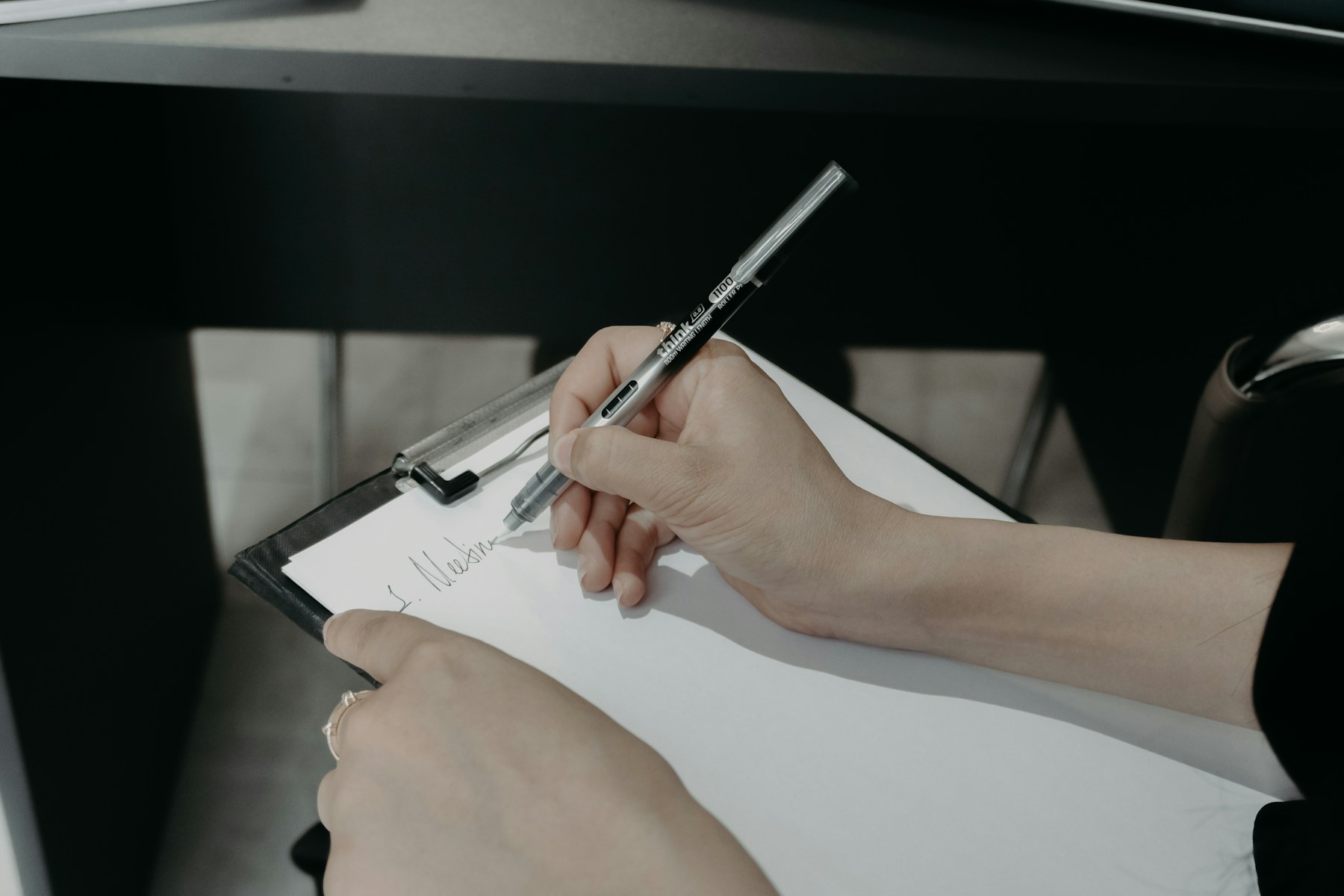 main qui remplit et signe un document sur une planchette à pince