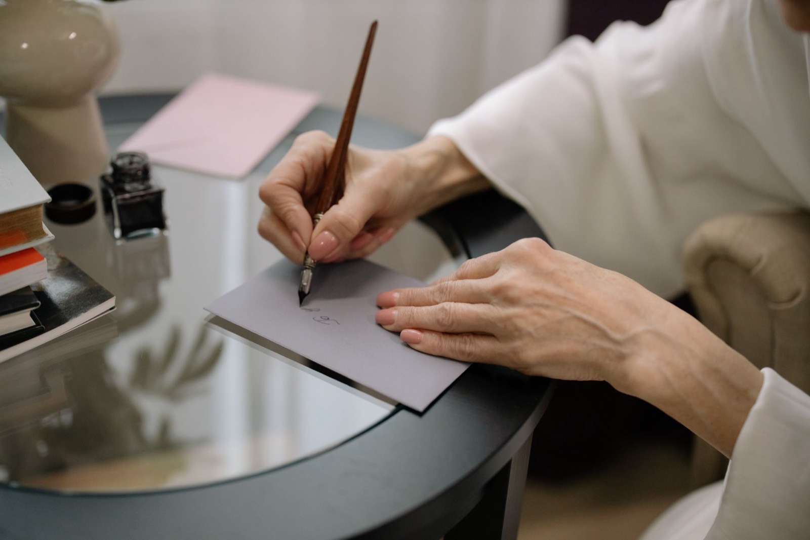 Personne qui écrit une lettre devant une enveloppe et des documents administratifs