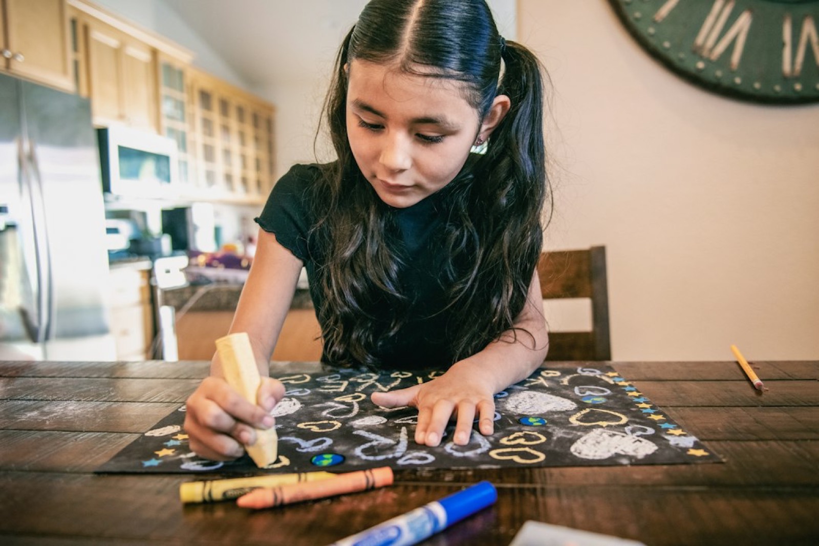 Un enfant dessine avec des crayons de couleur sur une table