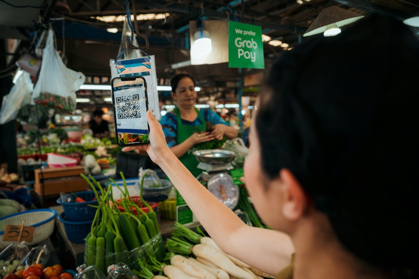 Vendeuse de marché recevant un paiement sur téléphone portable